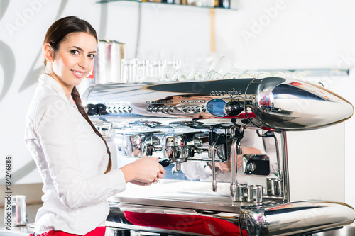 Young waitress using an automatic coffee machine
