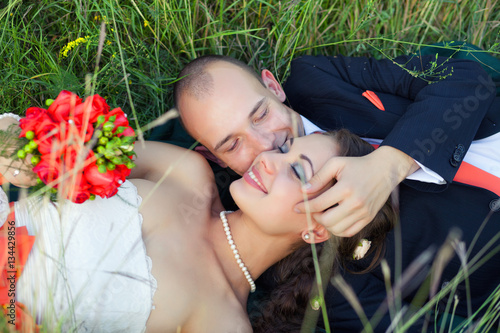 Bride and groom lying on green grass