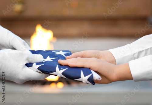 Poster Hands holding folded American flag on Eternal flame background