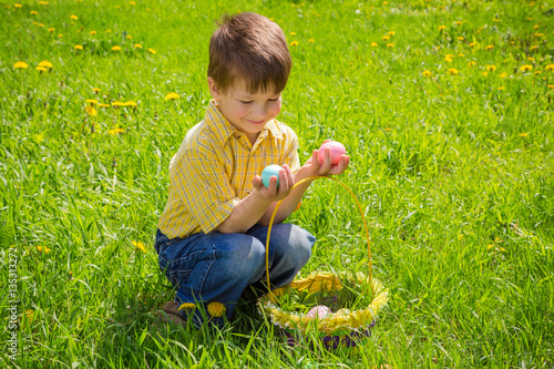 little kid with colorful easter eggs on green lawn