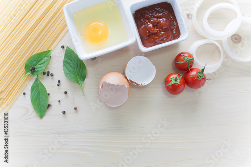 spaghetti with ingredients for cooking on wood background