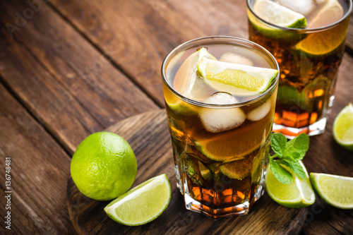 Poster Cuba Libre cocktail with cola, lime and ice in glass, cold longdrink
