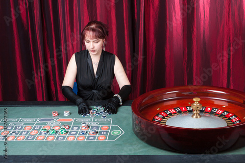 young woman wearing black gloves and black dress parlays in a casino Obraz na płótnie