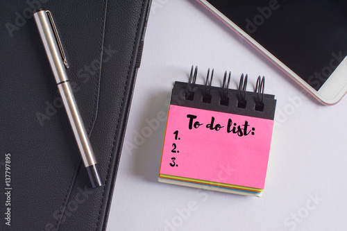 Poster "To do list" words on pink sticky notes with fountain pen, diary and smartphone