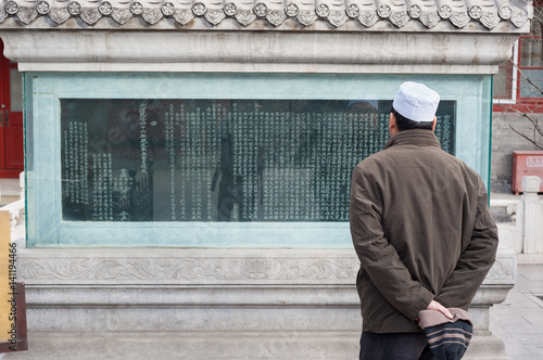 Poster Man reads an inscription on an ancient stele at Niujie Mosque, Beijing, China