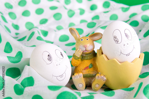 Poster Easter eggs with funny faces near bunny on polka dot tablecloth