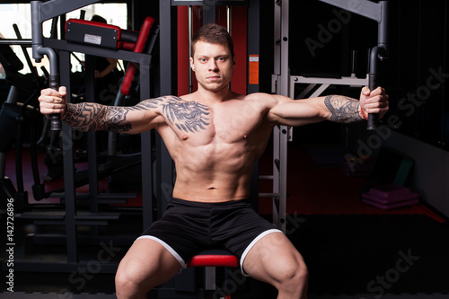 Poster Athletic man with naked torso performing crossover exercise for chest muscles at