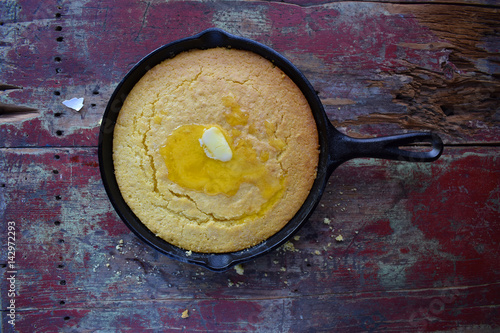 Yellow Cornbread in cast iron skillet on rustic wood table