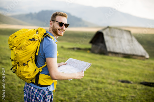 Young redhair man on mountain hiking holding a map