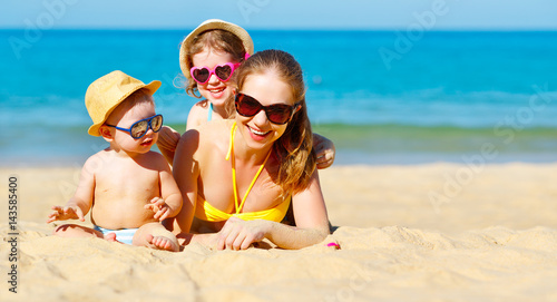 Happy family mother and children play and laugh on beach