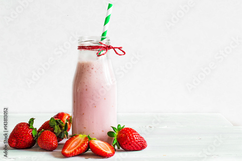 Strawberry smoothie or milkshake in a bottle with straw