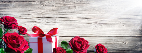 Gift Box And Roses On Vintage Wooden Background
