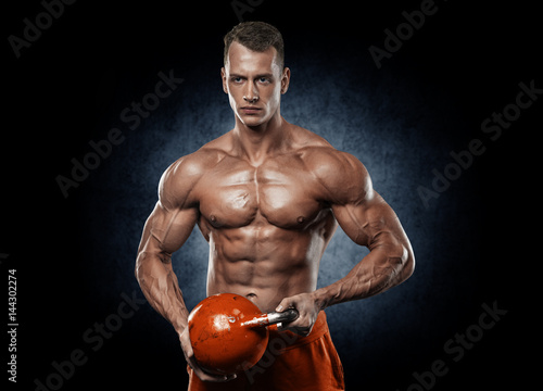 Poster Handsome man with big muscles, posing at the camera in the gym