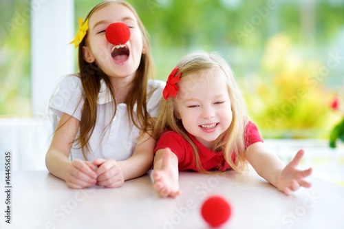 Poster Happy little sisters wearing red clown noses having fun together on sunny summer