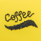 beans laid out in the word Coffee on a yellow background. good morning concept. minimal flat lay.