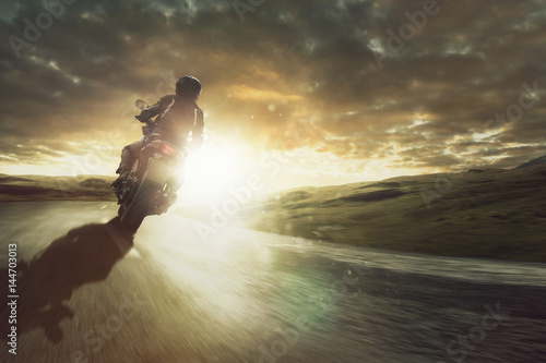 Motorrad fährt  durch eine Kurve bei Sonnenuntergang