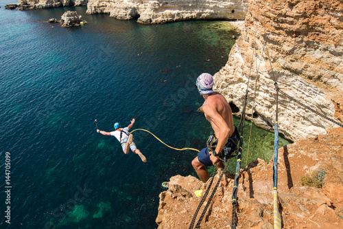 Rope jumping off a cliff with a rope in the water. The ocean. Sea. Mountain.