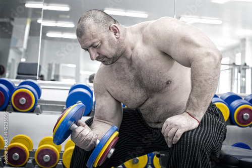 Poster The adult brutal man is engaged in power bodybuilding in the gym