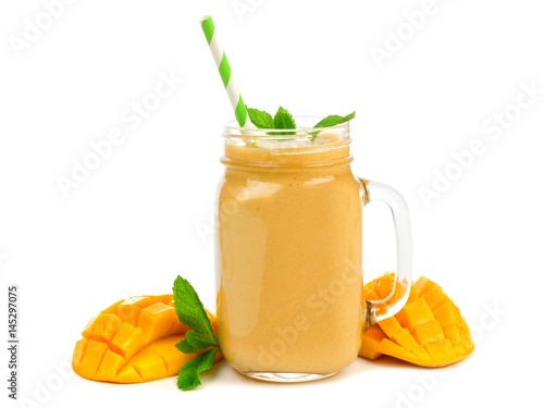 Mango coconut smoothie in a mason jar glass with mint and straw isolated on white