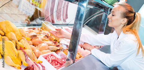 Female seller wearing uniform working with fresh meat