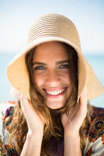 Portrait of happy young woman wearing hat at beach
