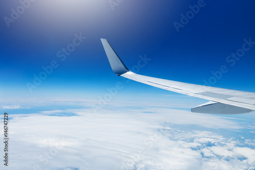 wing of an airplane flying high in the sky above the clouds