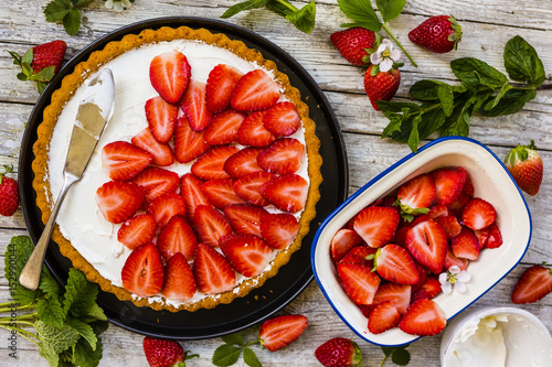 Delicious sponge cake with fresh strawberries on a wooden background.
