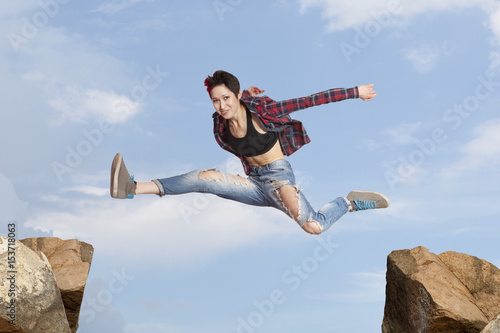 Woman jumping over the gap at blue sky