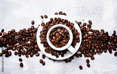  Roasted coffee beans in a white cup and saucer, gray food background, top view, flat lay