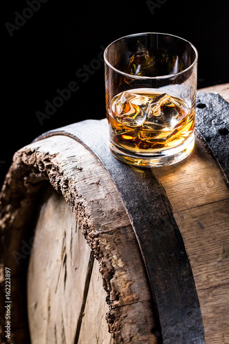 Glass of good whisky with ice in the distillery basement