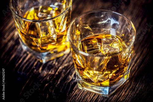 Whiskey drink. Whiskey drinks on rustic oak wood with ice cubes.