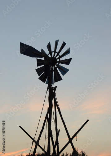 Spruce stems tied together scout-wise with rope in a tower-like struture carrying a wind turbine.