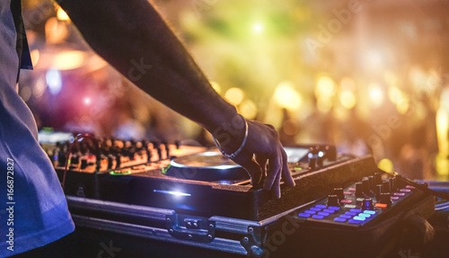 Dj mixing outdoor at beach party festival with crowd of people in background - Summer nightlife view of disco club outside - Soft focus on hand - Fun ,youth,entertainment and fest concept