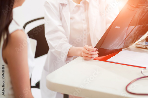 Female doctor holding the Mammogram film image and give advice her patient in consulting room.