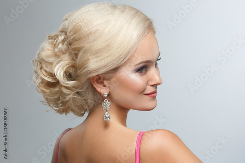 A smart wedding hairstyle on a blonde woman on a gray background. © ksi