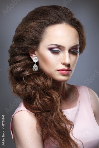 Beauty portrait of a girl with an elegant bridal woven voluminous hair on long dark hair. © ksi