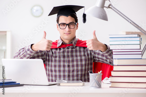 Super hero student wearing a mortarboard studying for exams