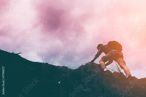 silhouette of man climbing steep mountain. Good image for adventure, struggle and success story photo.
