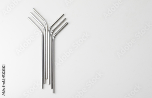 High angle view of six metal drinking straws arranged on white background © Natalie Board