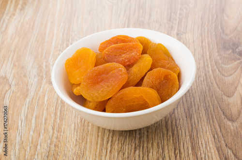 White glass bowl with dried apricots on table