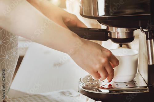 Woman making fresh espresso in coffee maker