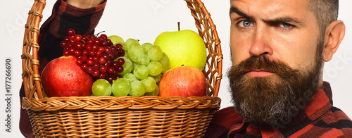 Man with beard holds basket with fruit on white background