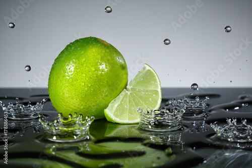 Lime with raindrops on grey background © i_arnaudov