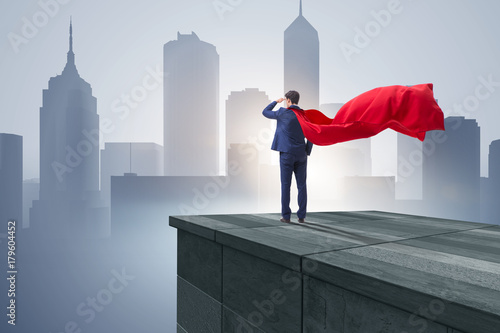 Super hero businessman on top of building ready for challenge