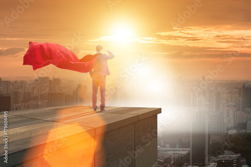 Super hero businessman on top of building ready for challenge