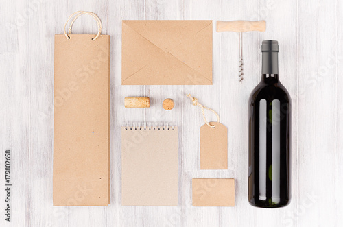 Corporate identity template for wine industry, blank brown kraft packaging, stationery, merchandise set with bottle red wine on soft white wood background.