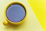 yellow mug with black coffee  on a yellow bright background.