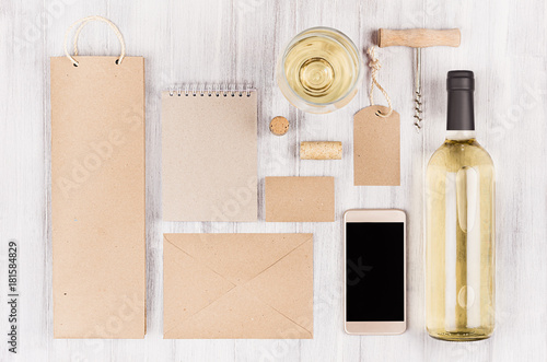 Corporate identity template for wine industry, packaging, stationery, phone, wineglass set with bottle white wine on soft white wood background.