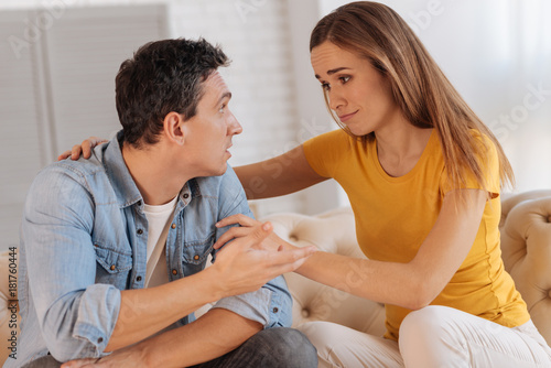 Understanding woman. Pretty cheerful young woman supporting her husband while sitting and listening to his story
