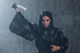 Martial arts Concept. Woman in kimono practicing with katana